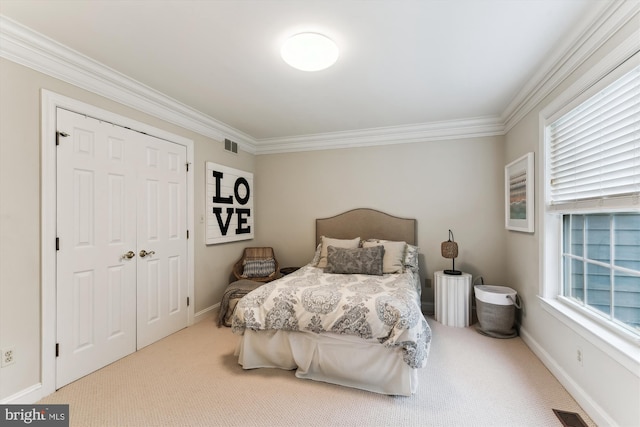 carpeted bedroom featuring crown molding, baseboards, and a closet
