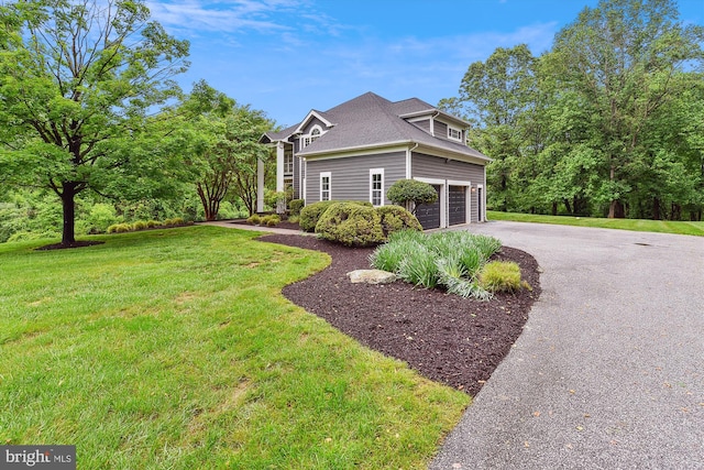 view of property exterior with asphalt driveway, a lawn, an attached garage, and a shingled roof