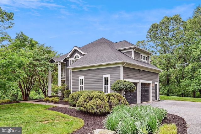 view of home's exterior featuring asphalt driveway, an attached garage, a lawn, and roof with shingles