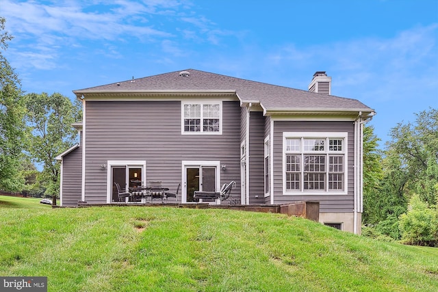 back of property with a lawn, a chimney, and a patio area