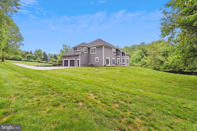 back of property with asphalt driveway, a garage, and a lawn