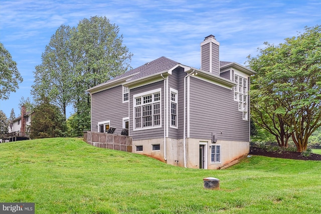view of side of property featuring a chimney and a yard