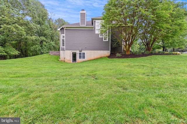 view of side of home with a chimney and a lawn