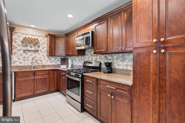 328 W Bay Front Rd, Lothian, MD 20711 - kitchen featuring appliances with stainless steel finishes, a sink, light tile patterned floors, light stone counters, and decorative backsplash