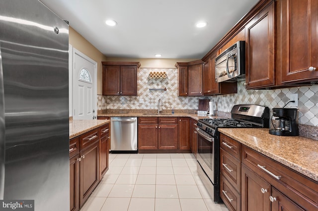 328 W Bay Front Rd, Lothian, MD 20711 - kitchen featuring stainless steel appliances, a sink, light tile patterned floors, decorative backsplash, and light stone counters