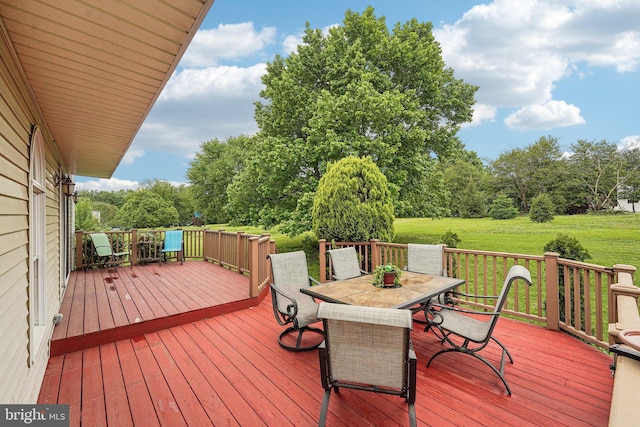 deck with outdoor dining space, a yard, and view of scattered trees