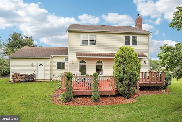 back of property with a deck, a chimney, and a lawn