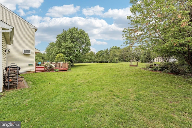 view of green lawn with a wooden deck and a wall unit AC