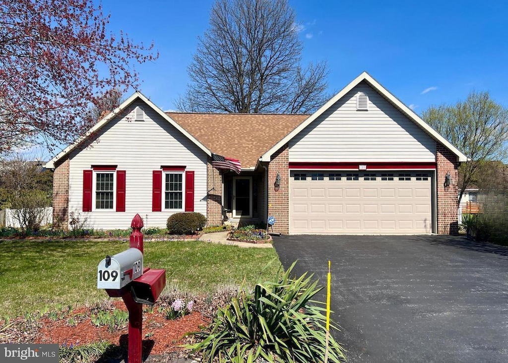 view of front of home with a garage, asphalt driveway, brick siding, and a front lawn