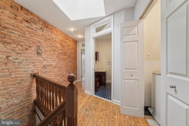 109 N Collington Ave, Baltimore, MD 21231 - corridor featuring brick wall, light wood-type flooring, and an upstairs landing