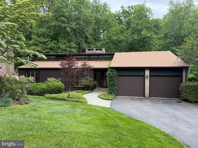 mid-century inspired home with asphalt driveway, a front lawn, a garage, and roof with shingles
