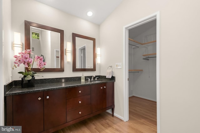 bathroom with wood finished floors, double vanity, and baseboards