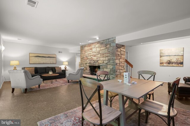 dining room featuring speckled floor and a stone fireplace