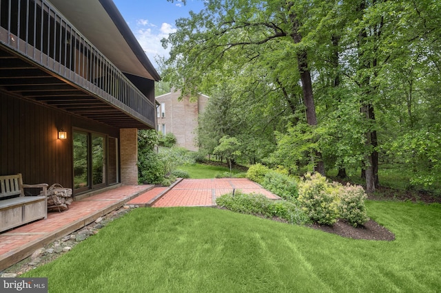 view of green lawn with a patio and a balcony