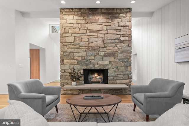 living room with wood finished floors, a stone fireplace, and recessed lighting