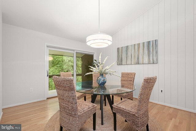 dining area featuring light wood-style flooring, baseboards, and wooden walls