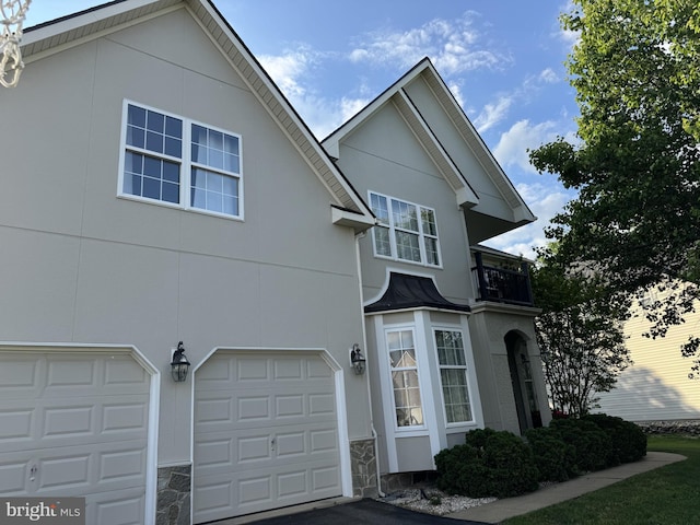 28 Blue Spruce Dr, Bear, DE 19701 - view of front of house featuring a balcony, an attached garage, stucco siding, and stone siding