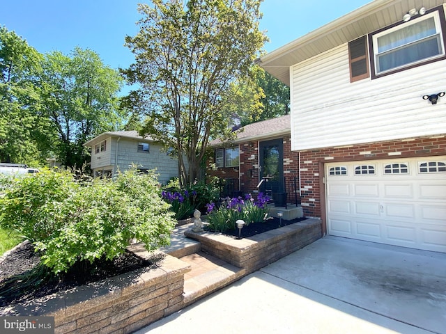 tri-level home featuring brick siding, concrete driveway, and an attached garage