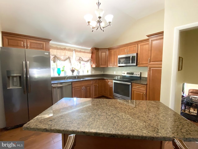 kitchen with stainless steel appliances, a chandelier, wood finished floors, lofted ceiling, and a breakfast bar area