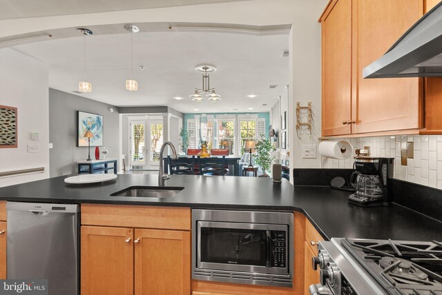 1418 N Rhodes St Unit B105, Arlington, VA 22209 - kitchen featuring stainless steel appliances, wall chimney range hood, a sink, dark countertops, and backsplash