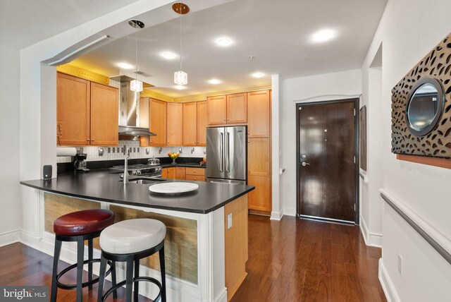 1418 N Rhodes St Unit B105, Arlington, VA 22209 - kitchen with appliances with stainless steel finishes, wall chimney exhaust hood, dark countertops, dark wood finished floors, and a peninsula