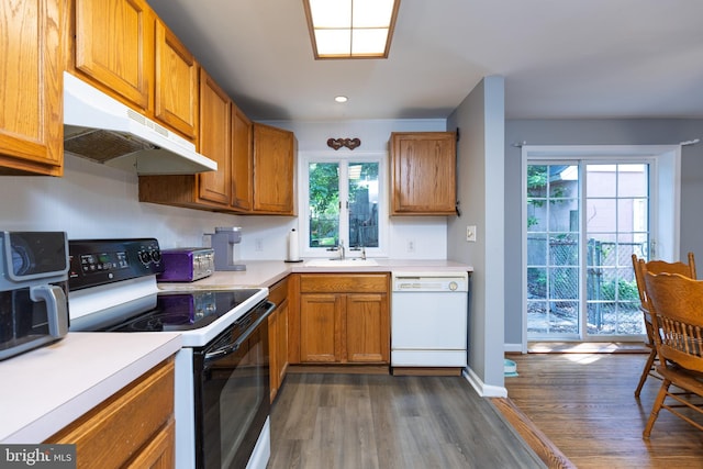 kitchen featuring electric range, white dishwasher, under cabinet range hood, dark wood-style floors, and a sink