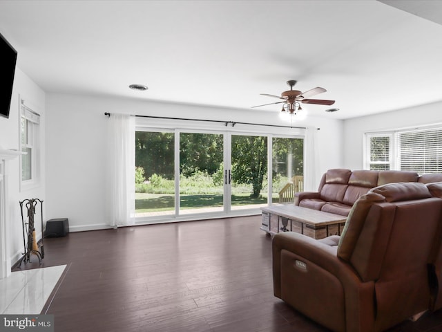 living area with plenty of natural light, a ceiling fan, and dark wood-style flooring