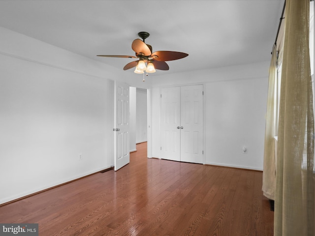 unfurnished bedroom with baseboards, wood finished floors, a ceiling fan, and a closet