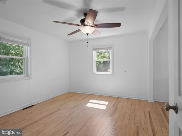 spare room featuring light wood-style flooring, a ceiling fan, and baseboards