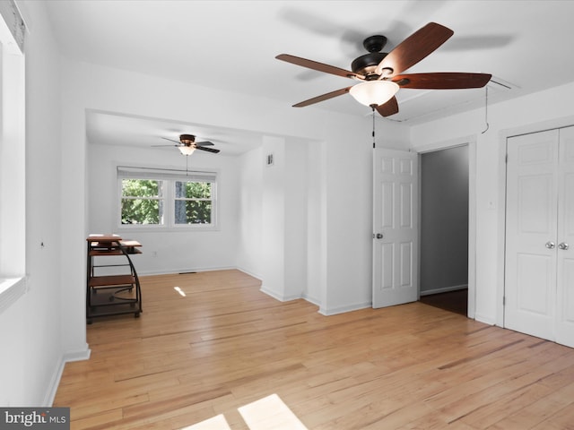 unfurnished room featuring a ceiling fan, attic access, light wood-style flooring, and baseboards