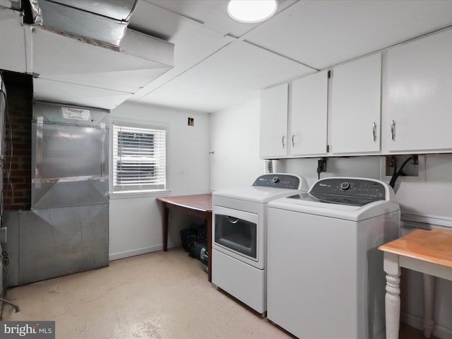 washroom featuring washing machine and dryer, cabinet space, and baseboards