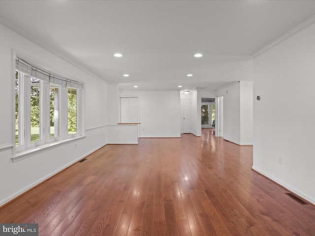 unfurnished living room with plenty of natural light, hardwood / wood-style floors, recessed lighting, crown molding, and baseboards