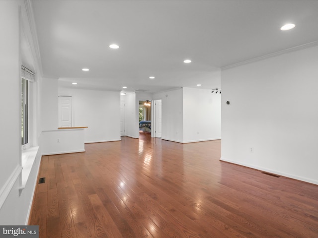 unfurnished living room with hardwood / wood-style floors, recessed lighting, plenty of natural light, ornamental molding, and baseboards