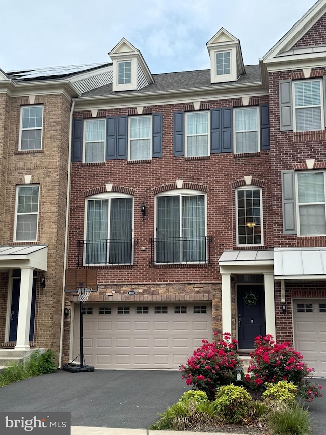 multi unit property featuring a garage, asphalt driveway, and brick siding
