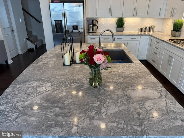 kitchen with stainless steel appliances, a sink, tasteful backsplash, and white cabinetry