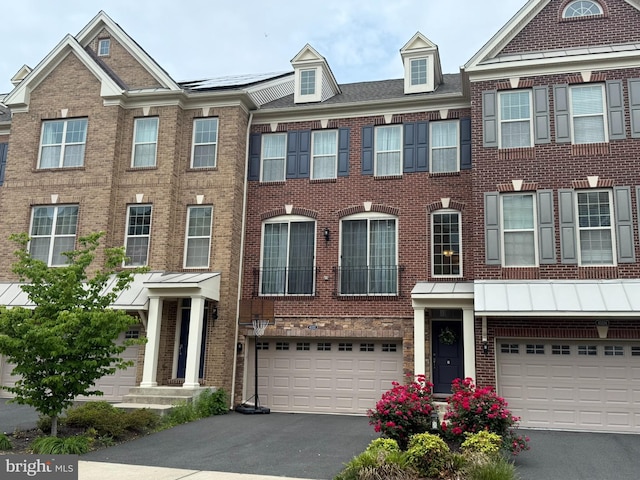 townhome / multi-family property with a garage, asphalt driveway, and brick siding