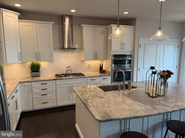 kitchen with wall chimney exhaust hood, appliances with stainless steel finishes, white cabinetry, dark wood-style flooring, and a breakfast bar area