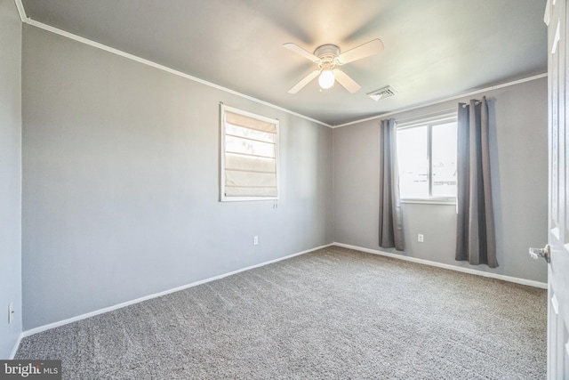 empty room featuring healthy amount of natural light, ceiling fan, ornamental molding, carpet flooring, and baseboards