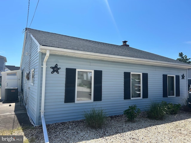 view of side of property with central AC unit and a chimney