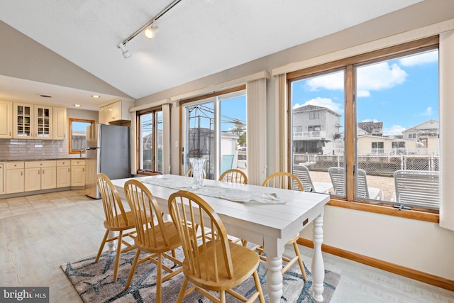 dining room with lofted ceiling, track lighting, and baseboards