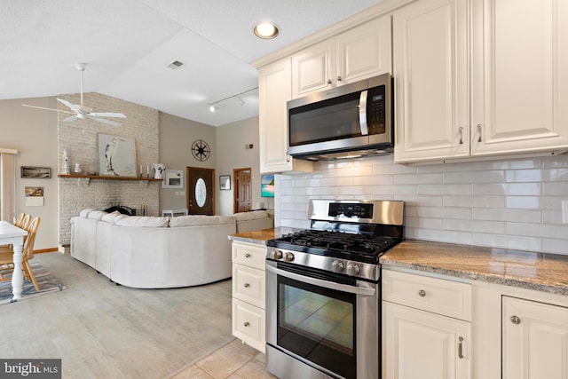 kitchen featuring appliances with stainless steel finishes, ceiling fan, lofted ceiling, open floor plan, and backsplash