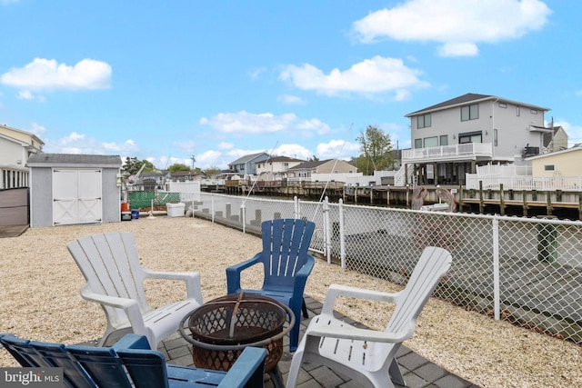 view of patio featuring an outdoor fire pit, a residential view, a fenced backyard, a storage unit, and an outbuilding