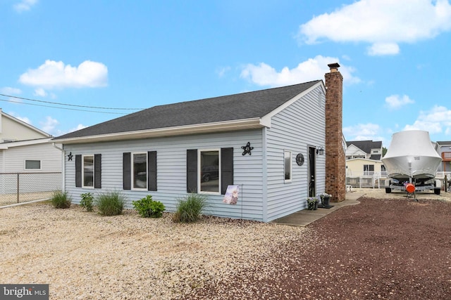 view of property exterior with a chimney, fence, and a shingled roof