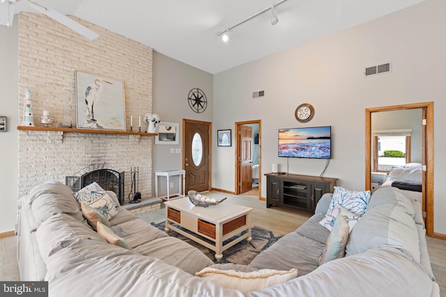 living area with high vaulted ceiling, rail lighting, baseboards, a fireplace, and wood finished floors
