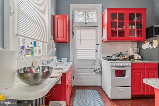 kitchen featuring gas range gas stove, dark wood-type flooring, plenty of natural light, and decorative backsplash