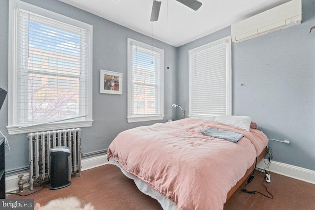 bedroom featuring radiator heating unit, a wall mounted air conditioner, baseboards, wood finished floors, and ceiling fan