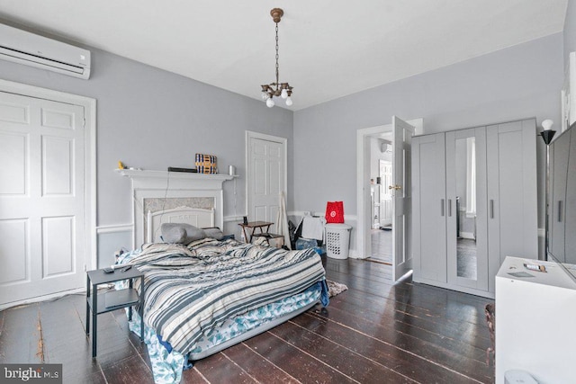 bedroom featuring a wall mounted AC, hardwood / wood-style flooring, and a chandelier