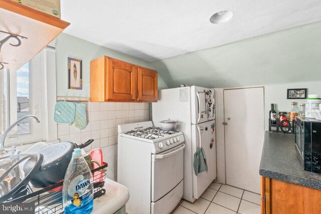 kitchen featuring gas range gas stove, brown cabinets, light tile patterned floors, tile walls, and black microwave