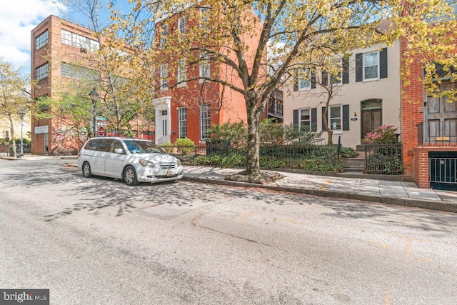 view of asphalt road with sidewalks, curbs, and street lights