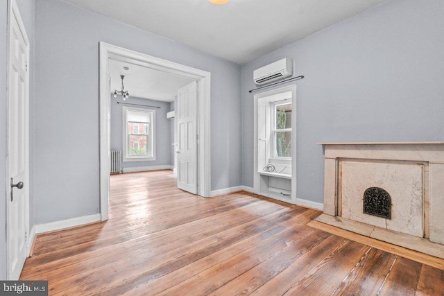 unfurnished living room with a wall mounted air conditioner, hardwood / wood-style flooring, radiator, and plenty of natural light